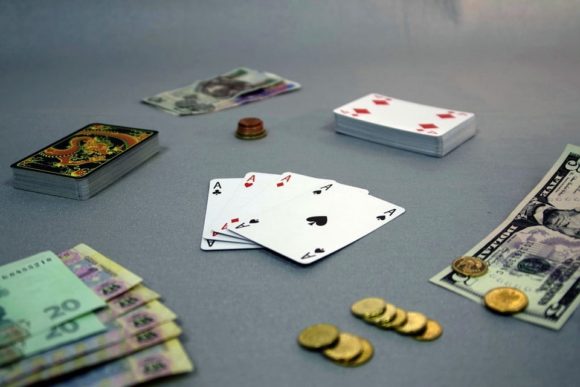 Fyrtal i ess omringat av fler spelkort, mynt och sedlar